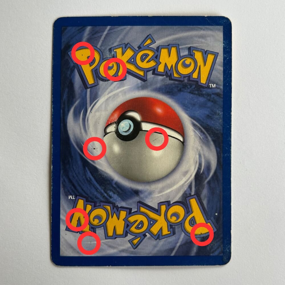 Baksidan av ett Pokémonkort där smuts och slitage längs kanterna är inringade i rött